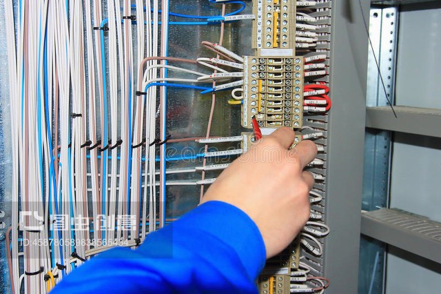 电工的手对电器柜的端子进行接线。The electrician`s hand carries out wiring to the terminals of the electrical cabinet.